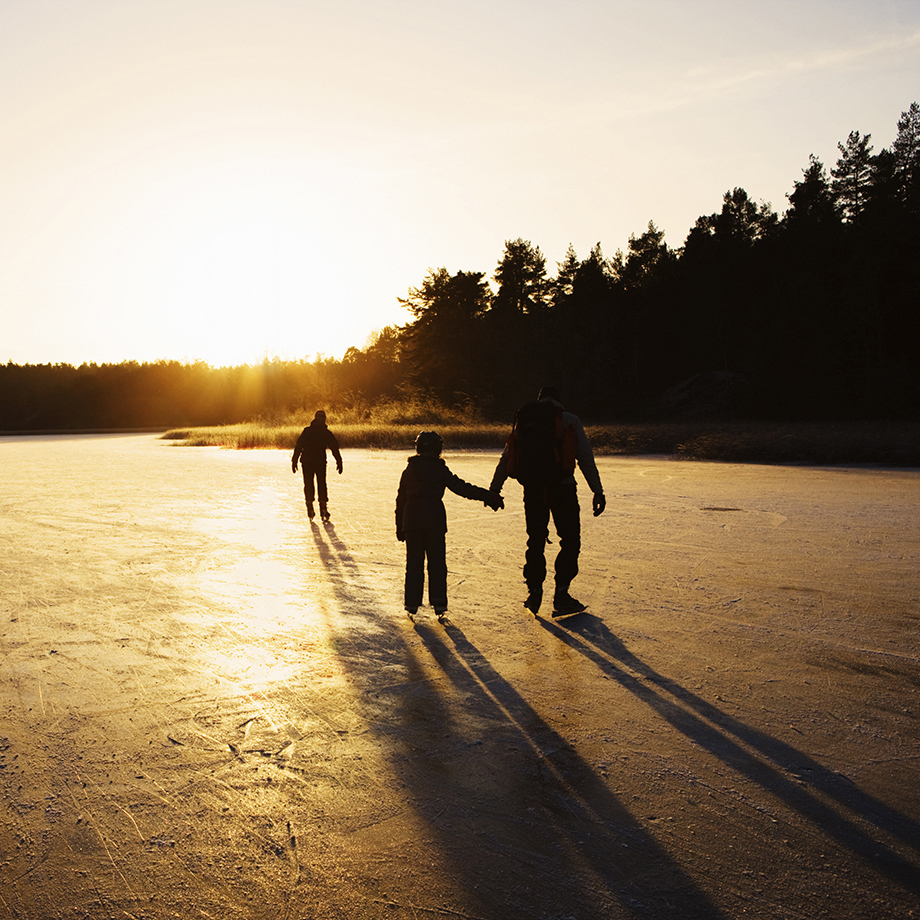 Father with two children skating on a lake Sweden